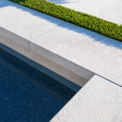 Detailed pool coping and architectural concrete edge beside clear water